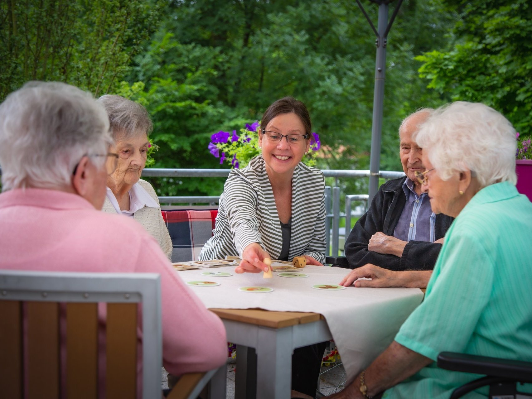 Eine Gruppe Bewohner spielen ein Würfelspiel auf der Terasse