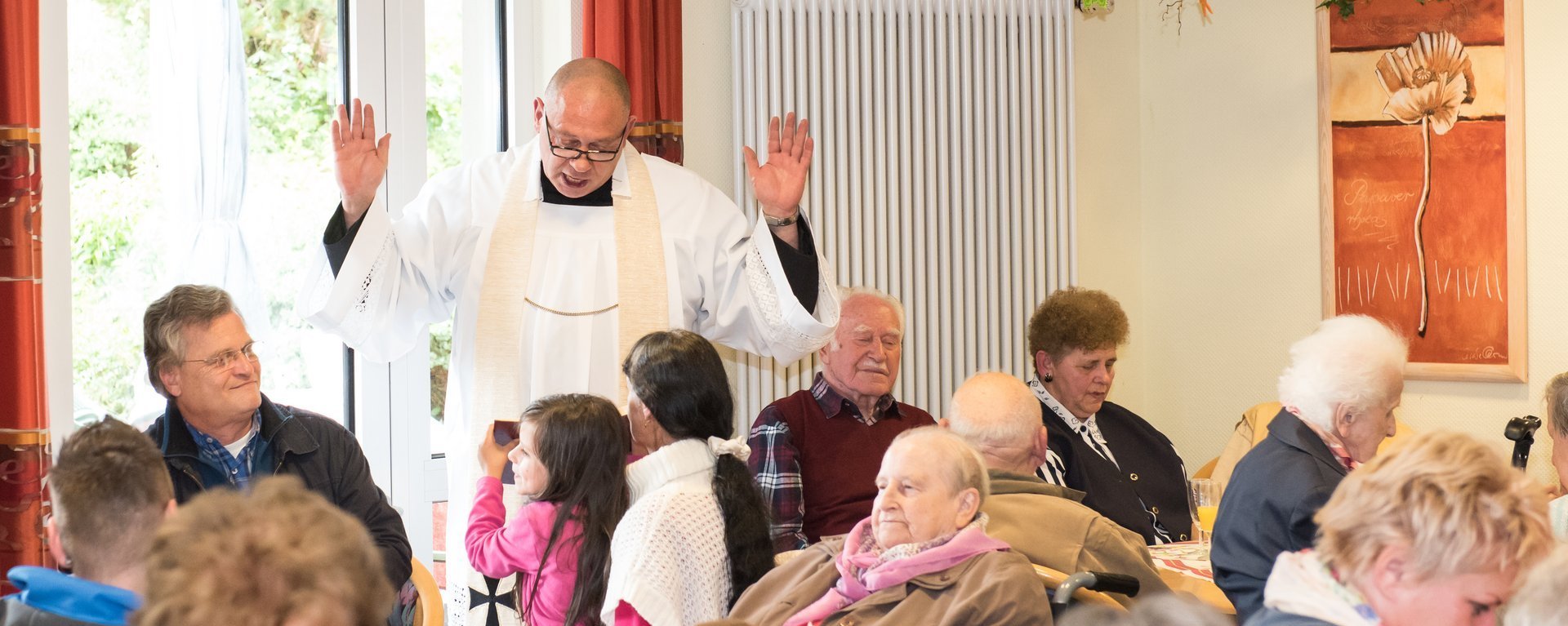 Im Wohnheim: ein Pfarrer predigt aus der Bibel zu den Bewohnern