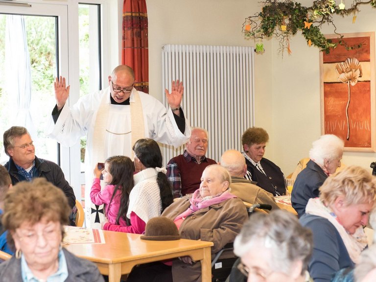 Im Wohnheim: ein Pfarrer predigt aus der Bibel zu den Bewohnern