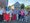 Eine Gruppe von etwa zwanzig Personen posiert im Sommer für ein Gruppenfoto vor einem Backsteingebäude. Im Hintergrund sind ein Wohnhaus, Fahrräder und ein roter Anhänger zu erkennen. Eine Frau in der vorderen Reihe hält ein Zertifikat in den Händen.