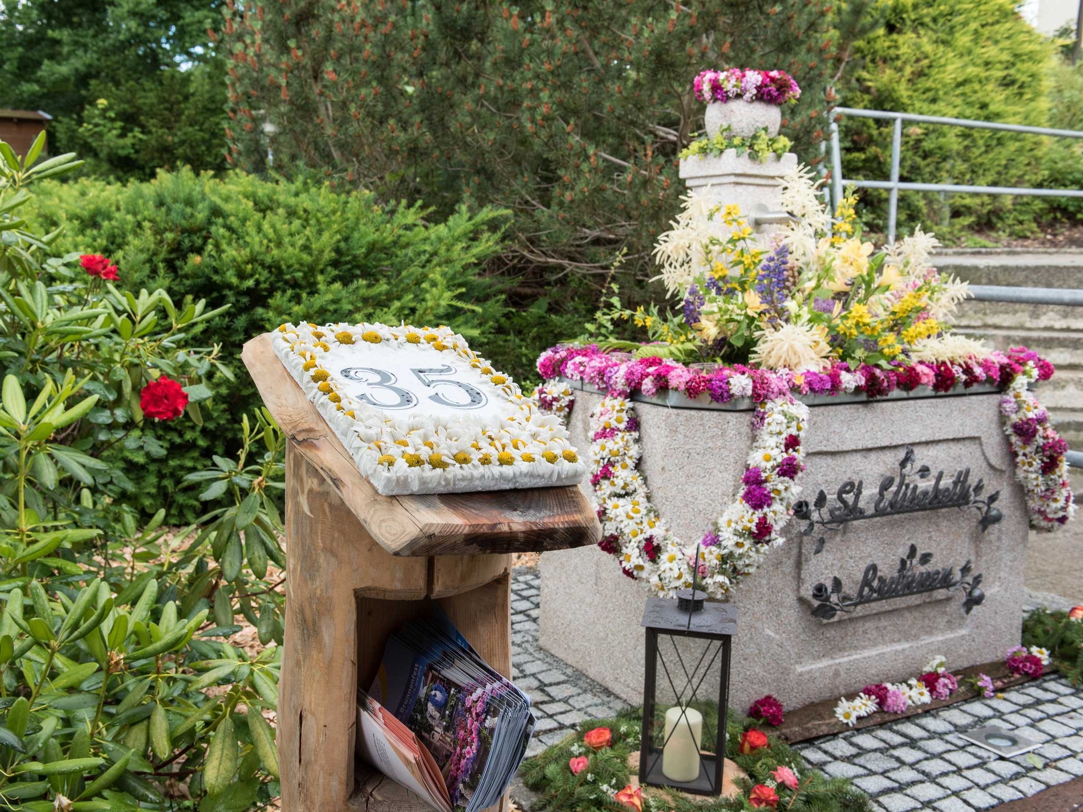 ein mit Blumen geschmückter Steinbrunnen und eine Tafel auf der 35 steht